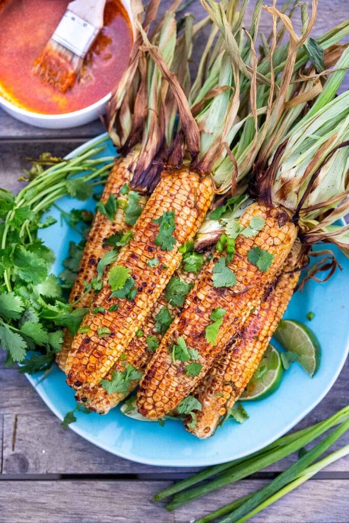 plate of Mexican grilled corn with fresh cilantro, served with lime wedges. 