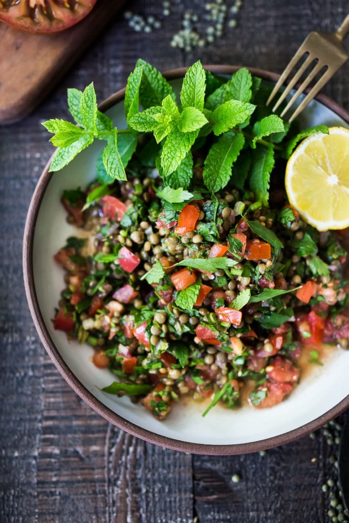 lentil tabouli salad with tomatoes and herbs, served with fresh lemon.