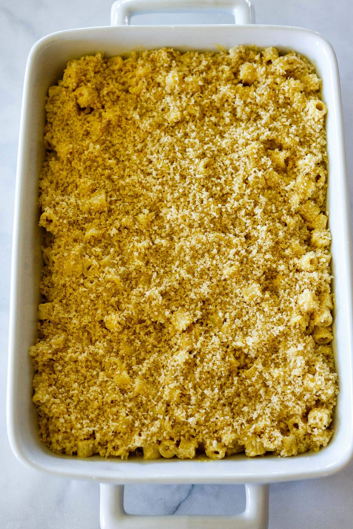 vegan mac and cheese in baking pan topped with breadcrumb topping. 
