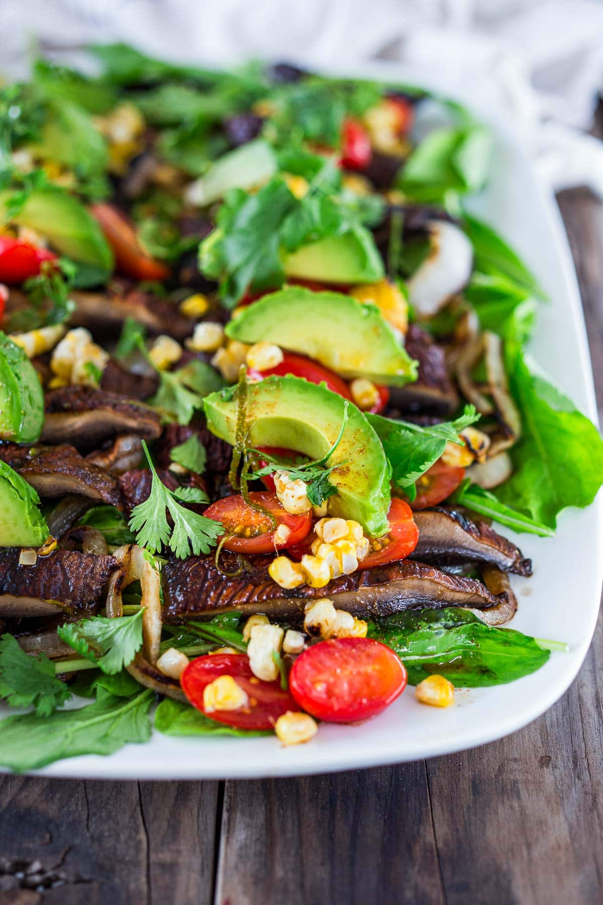 grilled portobello mushroom salad with grilled onions and corn, fresh avocado slices and cherry tomatoes, cilantro, and limes.