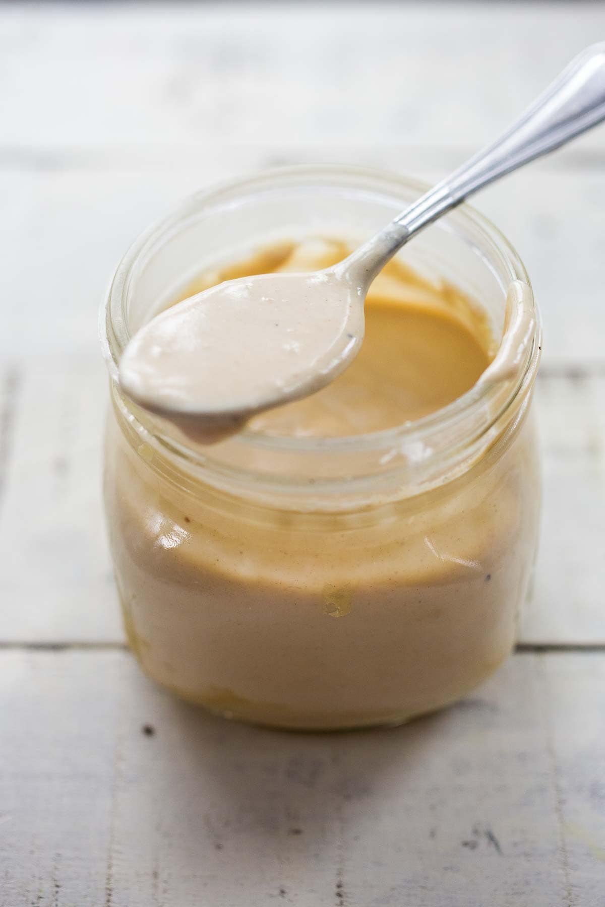 creamy tahini sauce in a jar with a spoon. 