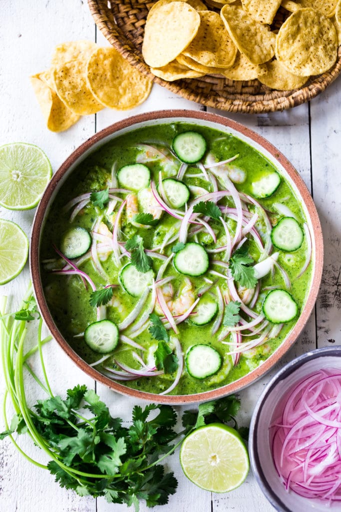 aguachile in serving dish with shrimp, red onion, cucumber, and cilantro.