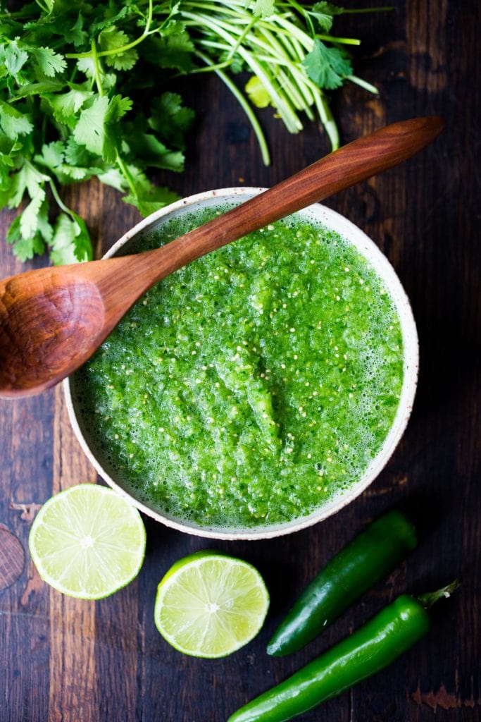 bowl of fresh salsa verde with wooden spoon.