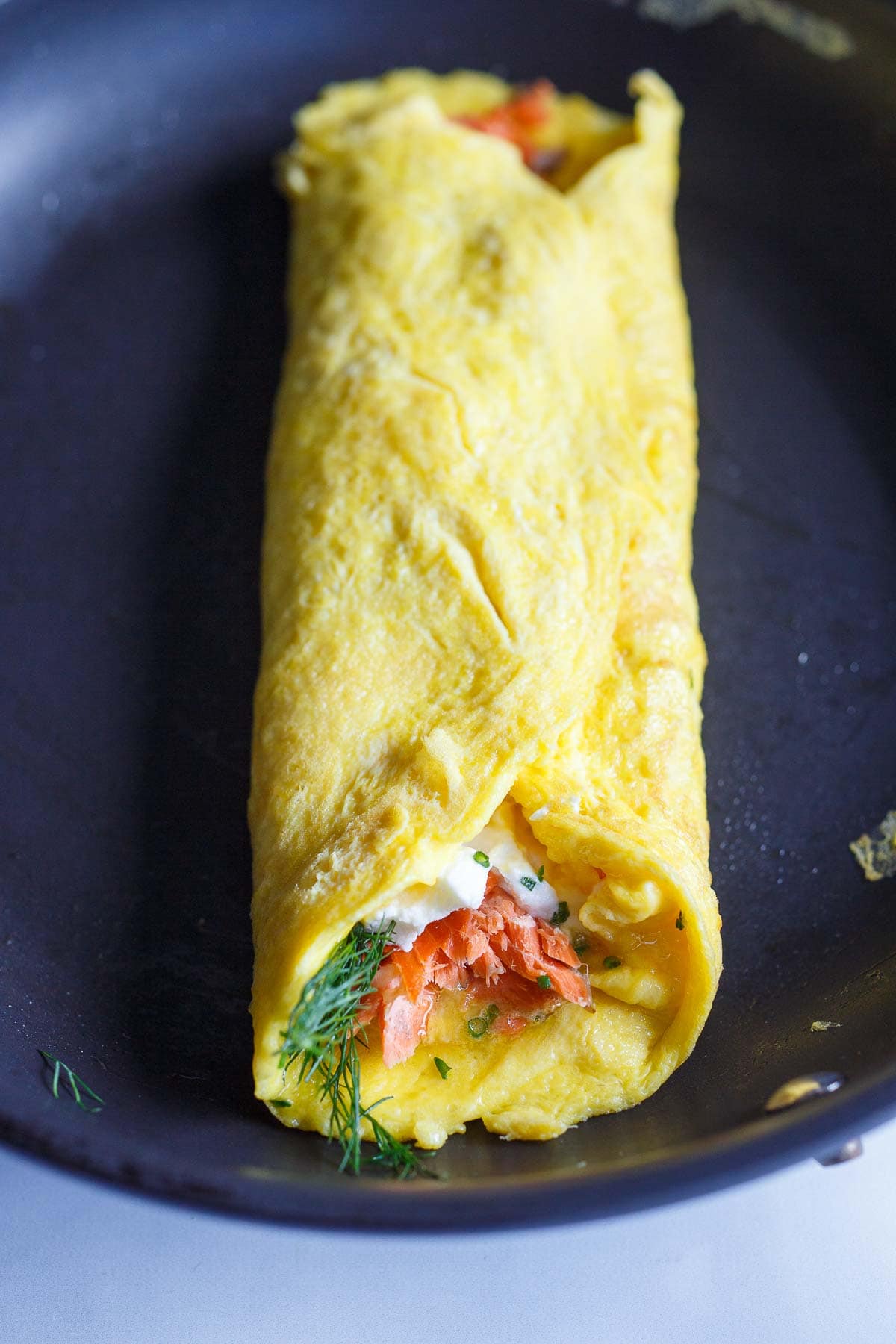 folded omelette in skillet, stuffed with flaky salmon, herbs, and goat cheese.