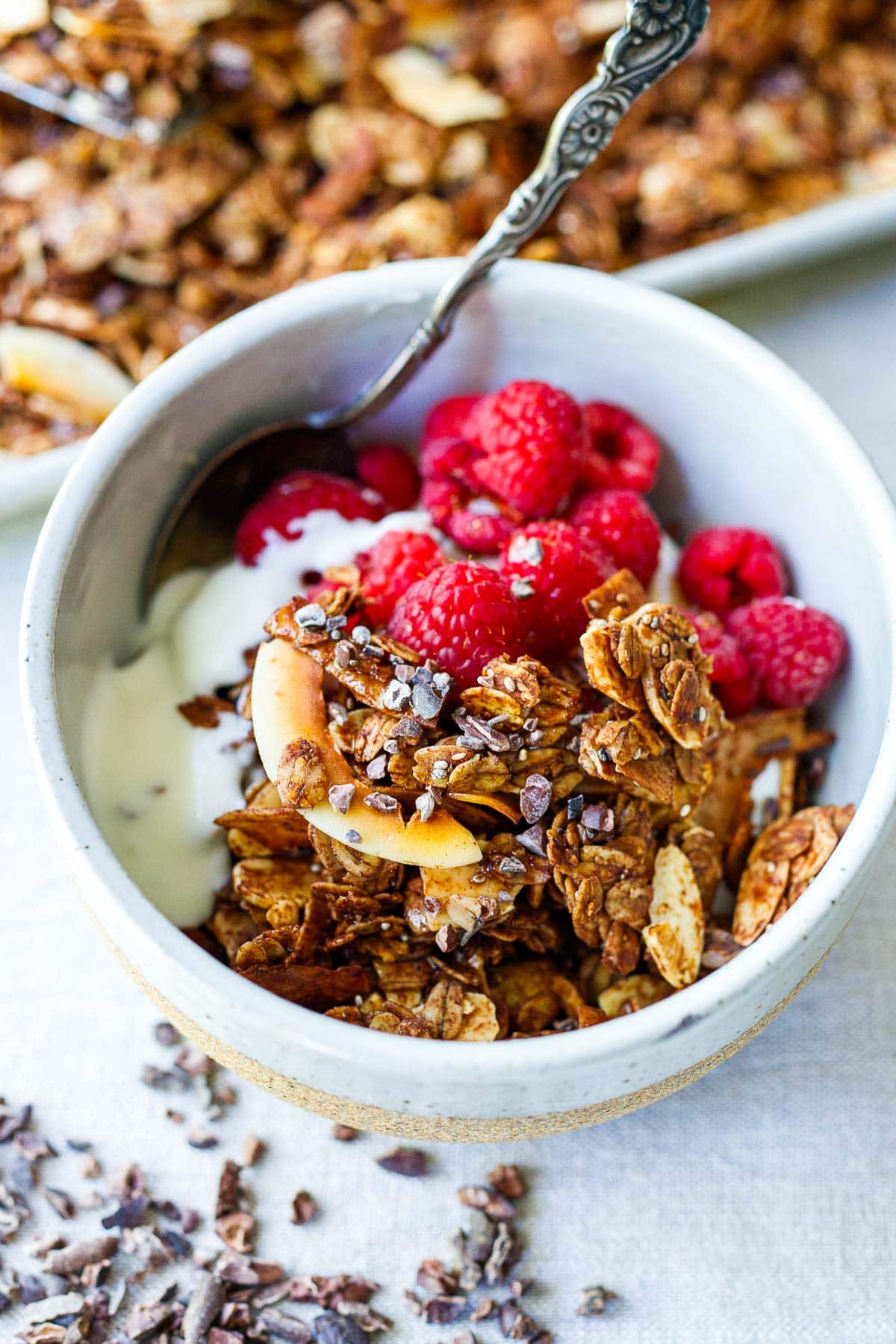 small bowl of yogurt and raspberries with dark chocolate granola on top. 