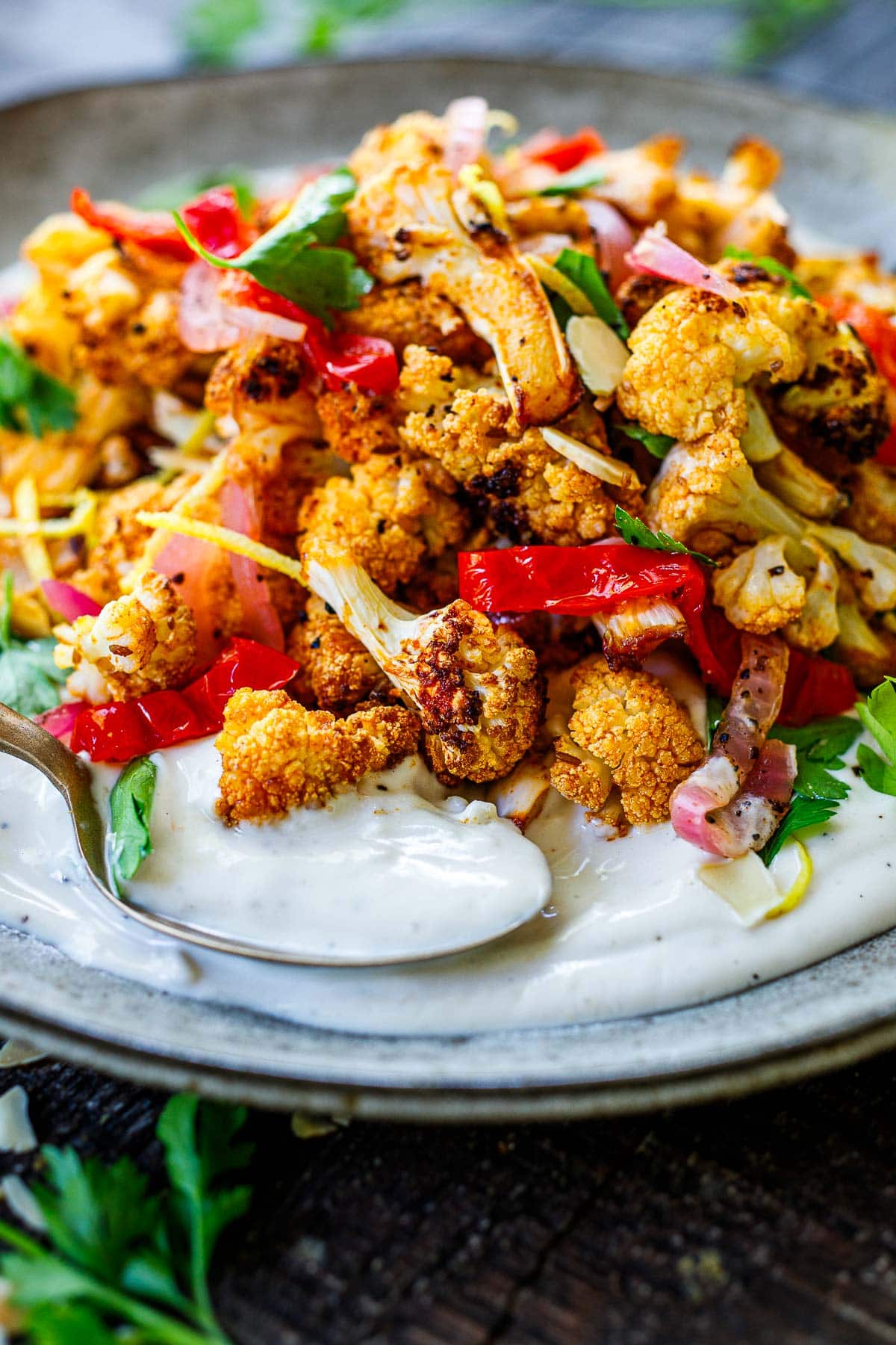crispy cauliflower garnished with pickled red onions, peppers, parsley, slivered almonds, and lemon zest, served over tahini yogurt. 