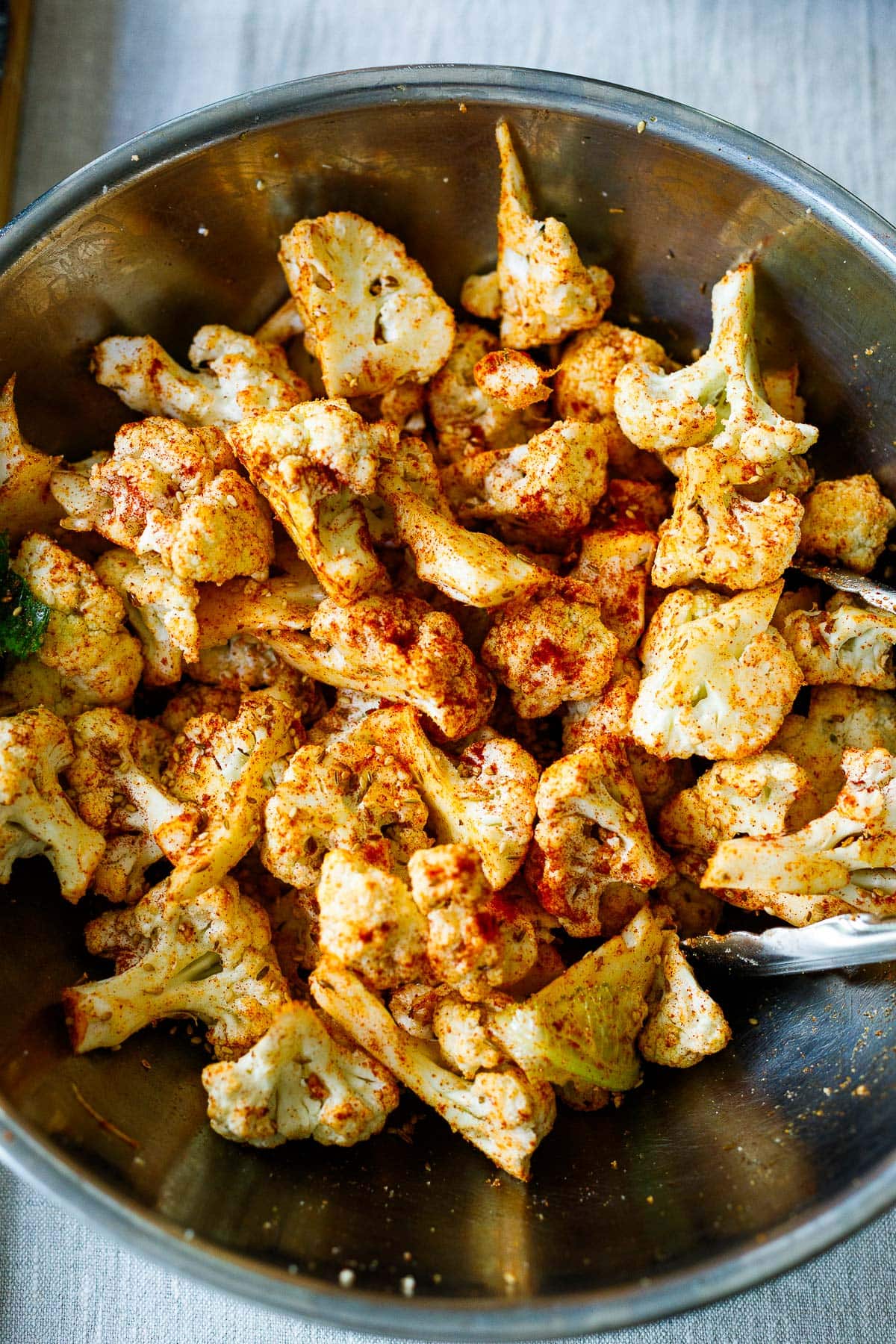 cauliflower florets in mixing bowl, tossed with spices. 