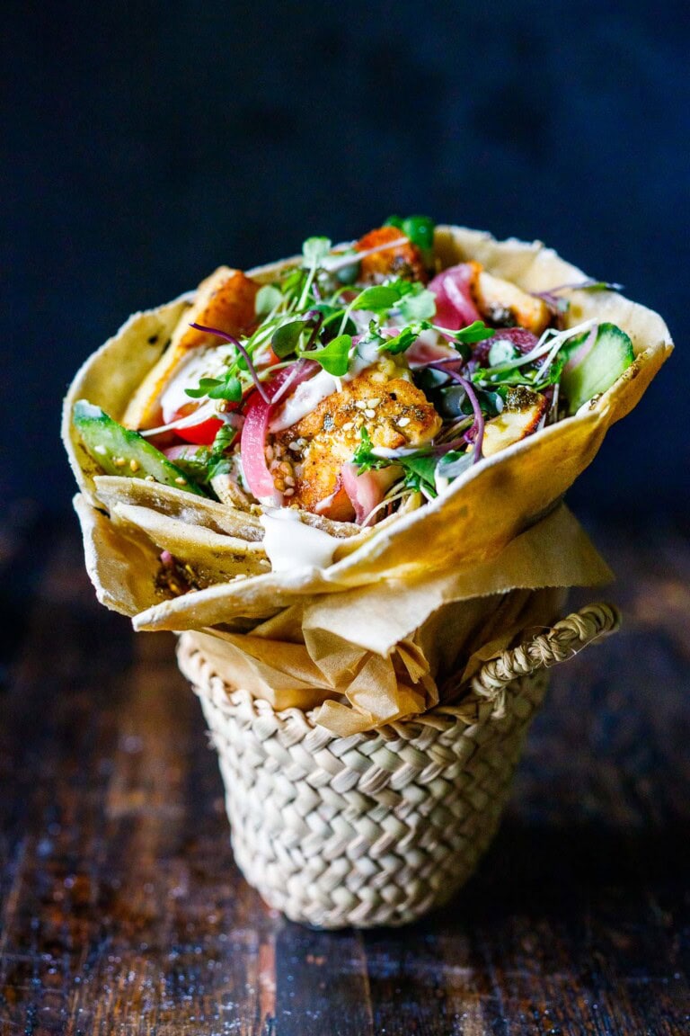 A halloumi wrap with tomatoes, microgreens, cucumbers and tahini yogurt dressing.