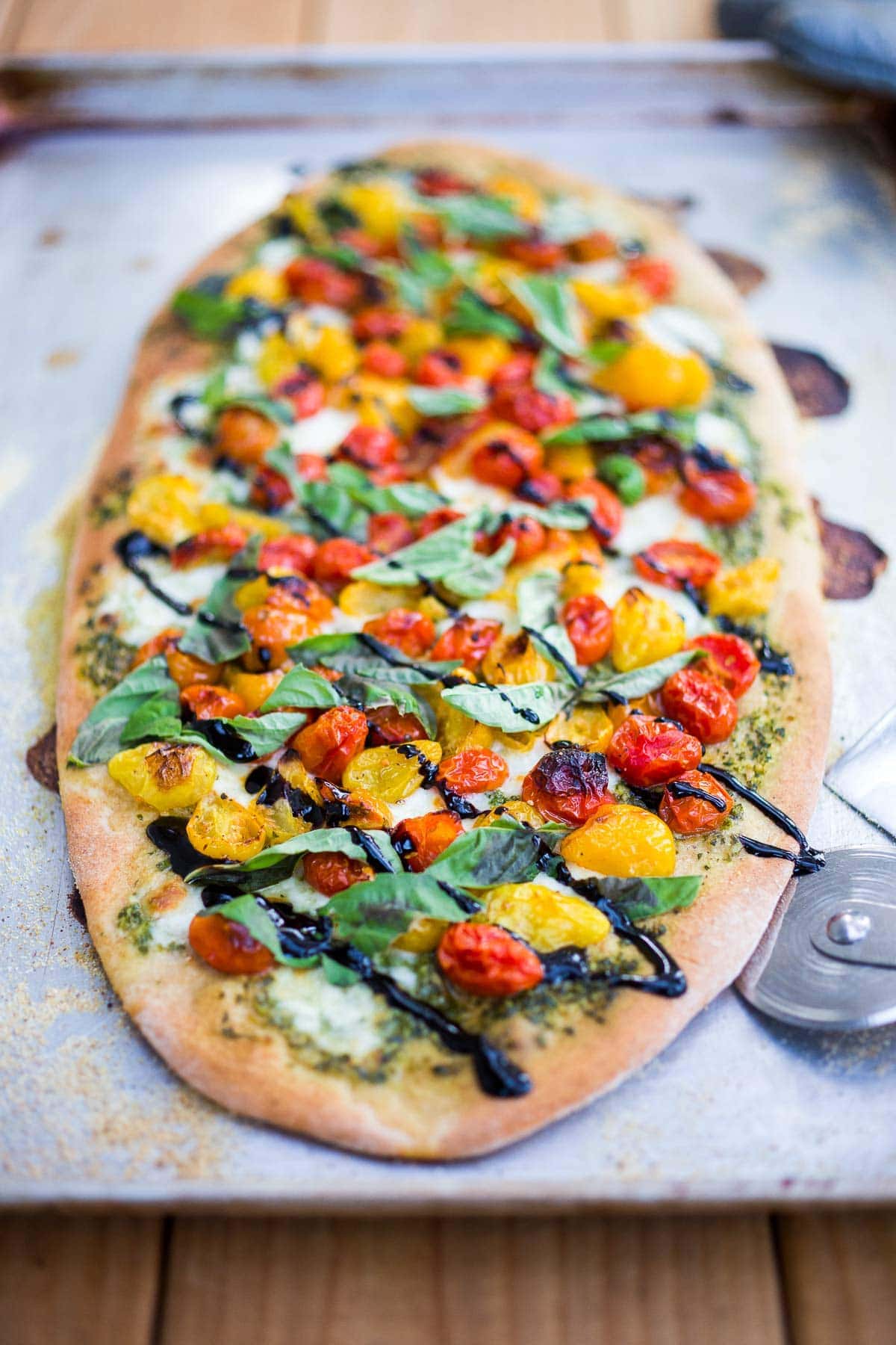 Make a simple, delicious Caprese Pizza with tomatoes, fresh mozzarella, basil leaves and basil oil topped with a balsamic glaze. Use store-bought pizza dough or make your own!
